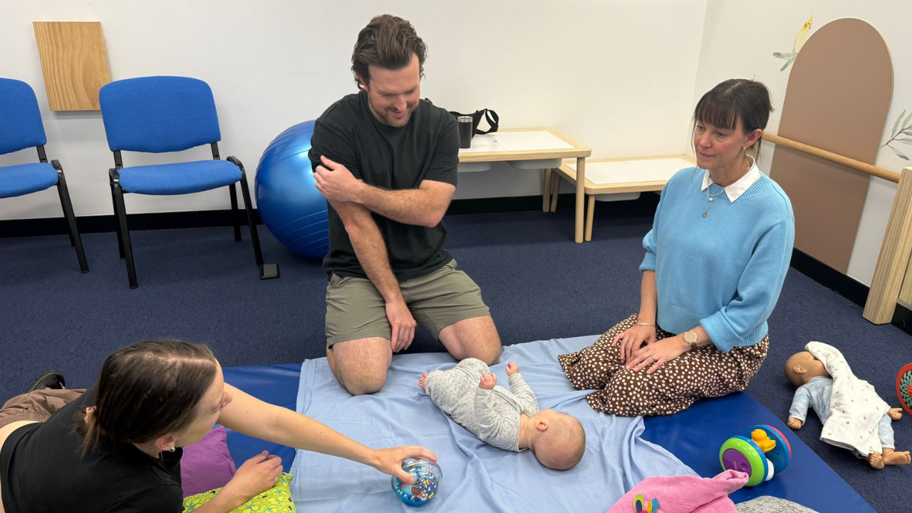 Baby and parents talking to a physiotherapist during an initial assessment at the Walky Talky Hub, discussing baby development and physiotherapy goals.