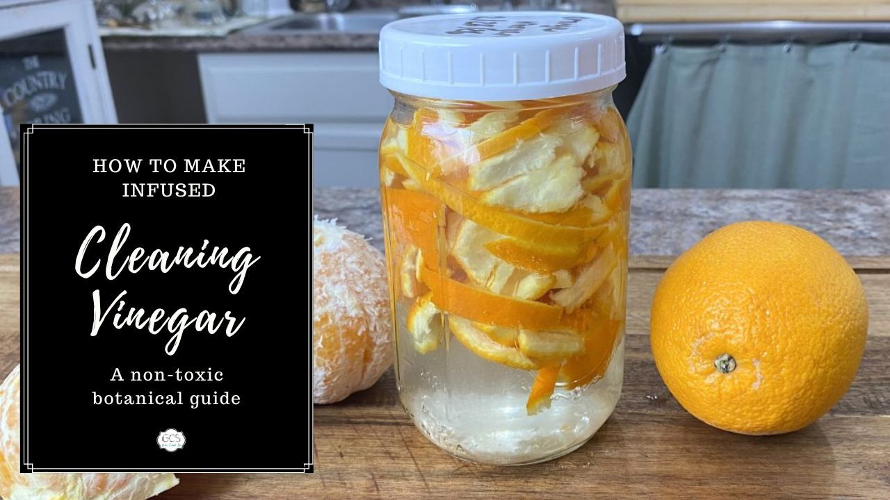 Orange peels with vinegar in a mason jar with a white lid, next to oranges on a wooden board