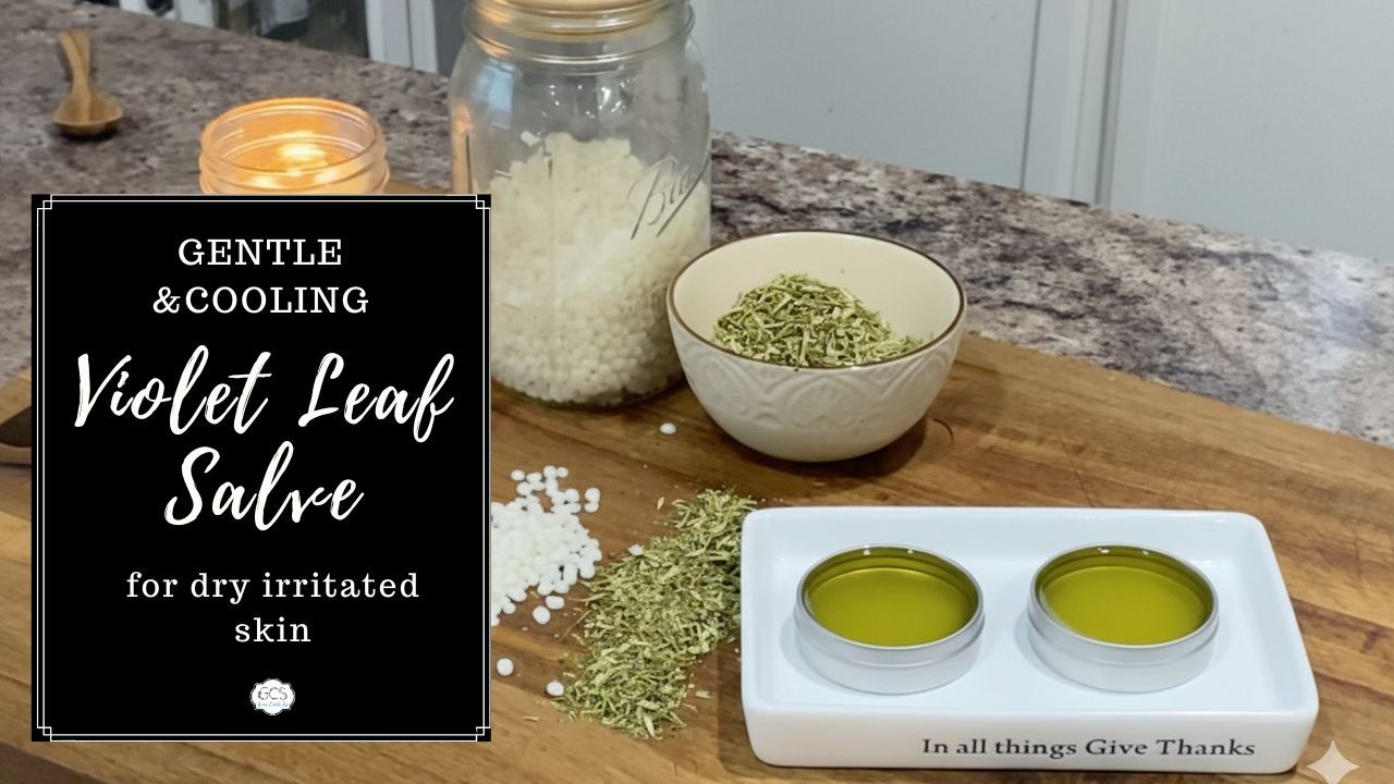 salve in container on a white plate on a wooden table with dried violet leaves and wax pebbles in jar with a candle burning 
