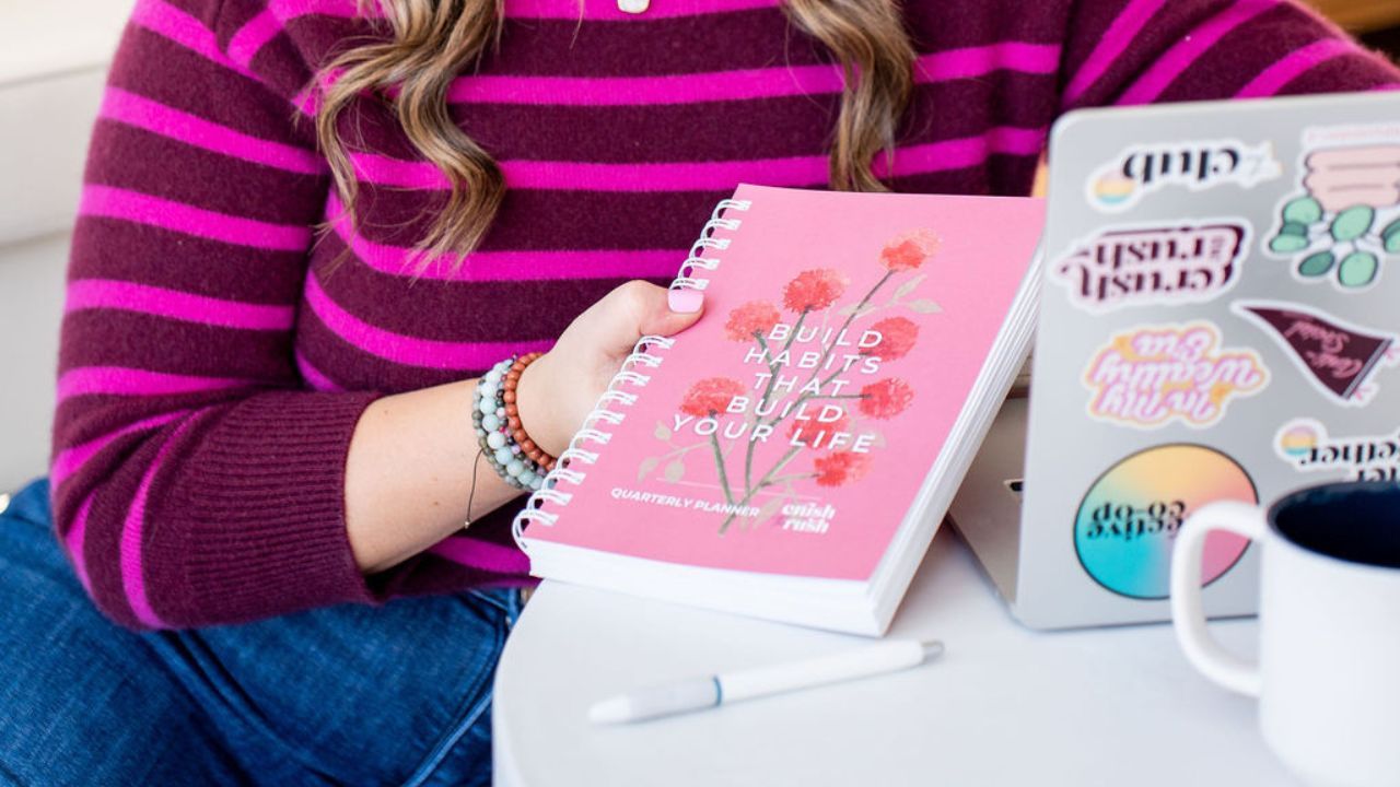 business strategist for female entrepreneurs Holly Haynes holding laptop and small business planner