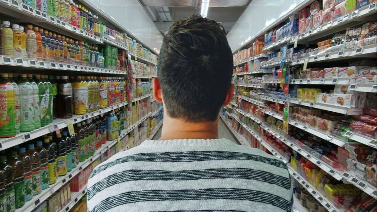 back of a man's head standing in an aisle of a grocery store