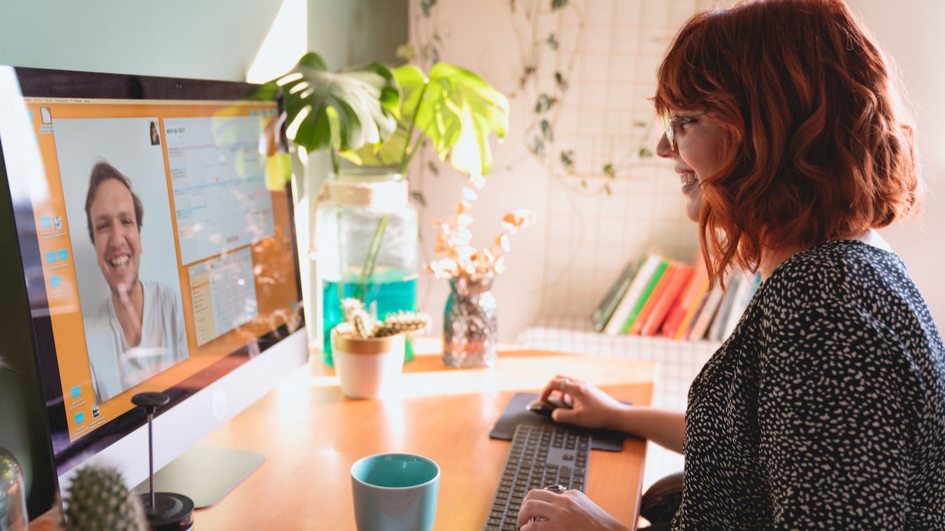 A woman smiling optimistically at a man on her computer screen.