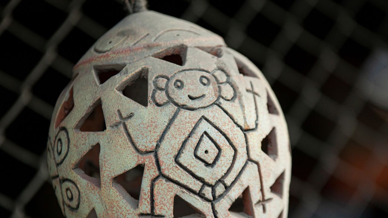 A Taino artifact is pictured: a white ceramic-style object with Taino carvings. 