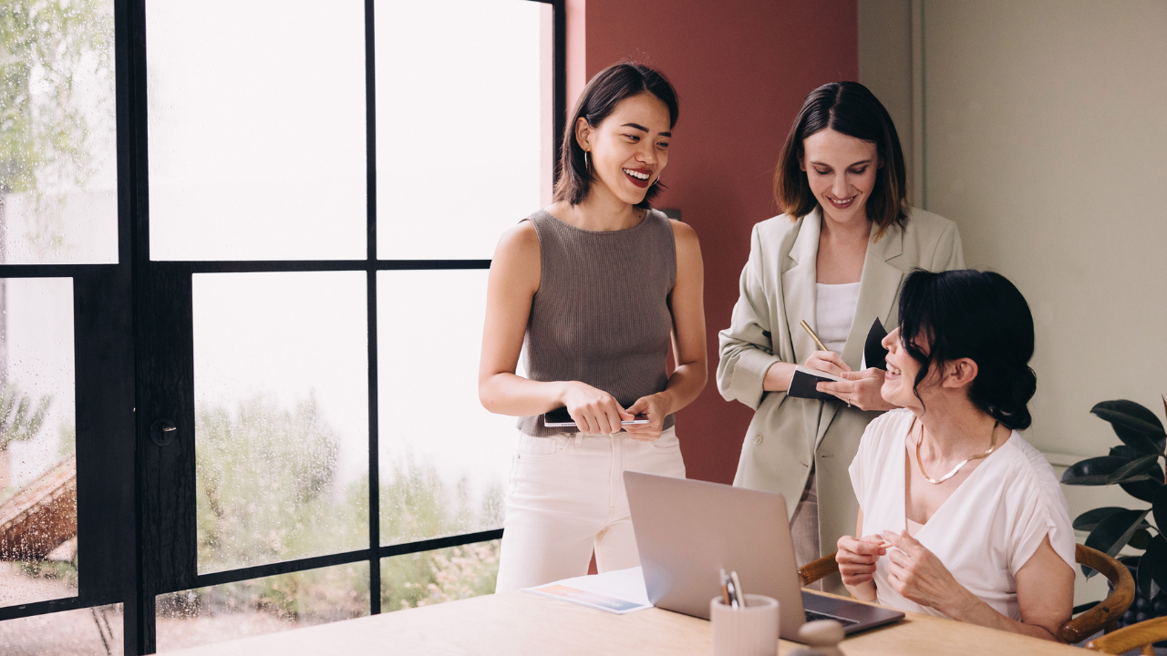 Women collaborating at a laptop, representing connection, empowerment, and supportive leadership among women in business.