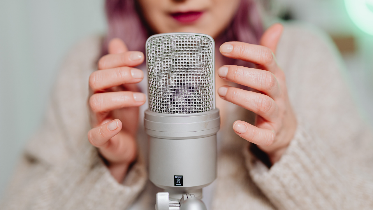 Female entrepreneur holding a silver podcast microphone, representing visibility and amplification for women in business and the launch of a global leadership podcast series.