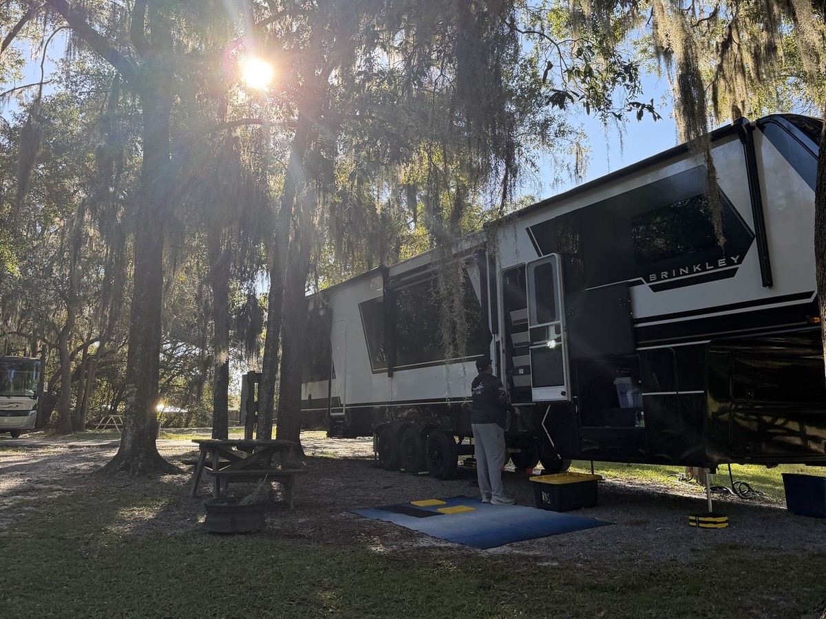 Fifth-wheel RV parked under Spanish moss at Country Oaks RV Park
