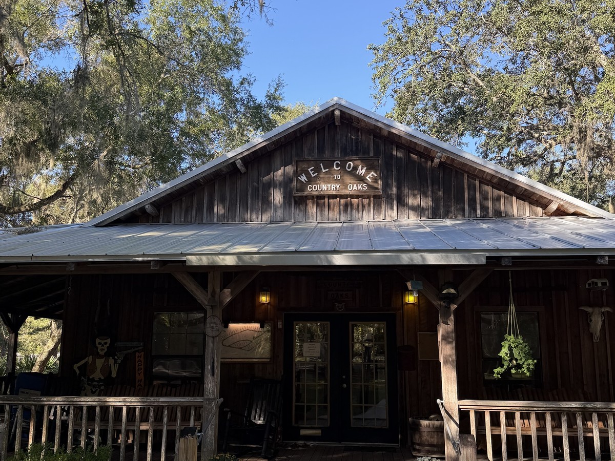Rustic wooden welcome building at Country Oaks RV Park in St. Marys, Georgia, under live oaks