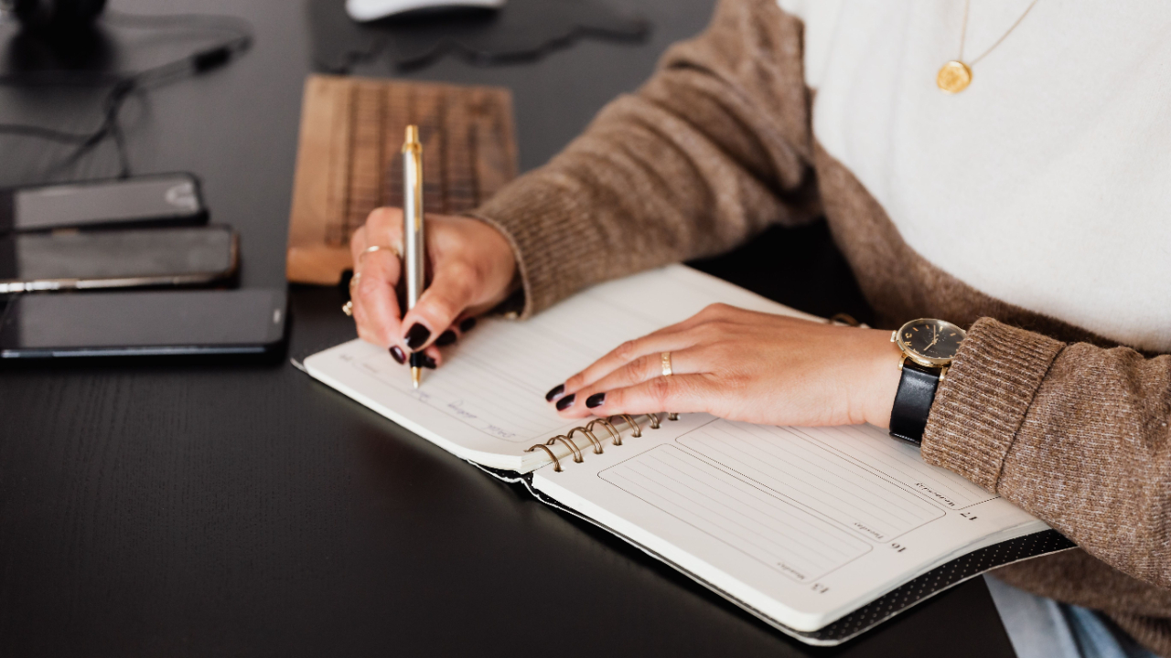 image of a person sitting in front of a desk while writing on a notebook