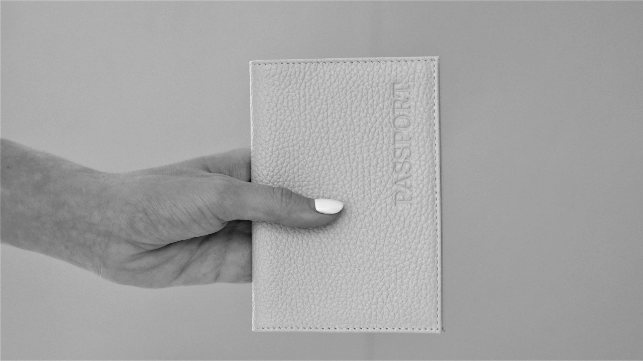 a black and white photo of a woman holding a passport cover leaf