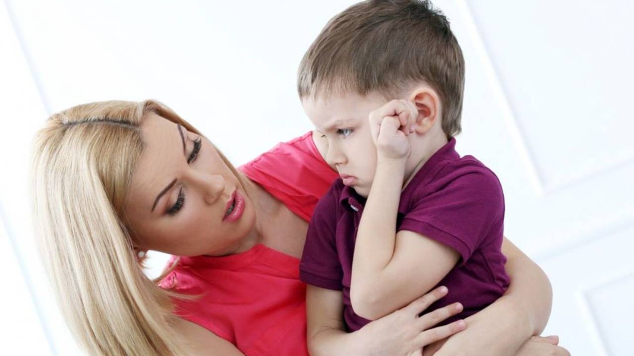 Calm parent sitting beside an upset child at home, offering support during an emotional moment