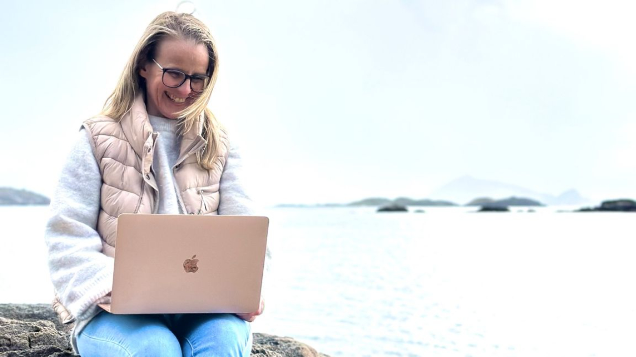 Kvinne sitter ute i naturen og jobber på laptop – bygger en sjelsbasert online business med frihet og fleksibilitet.