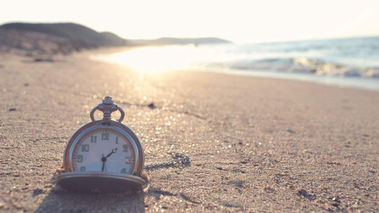 Clock on beach buried in sand