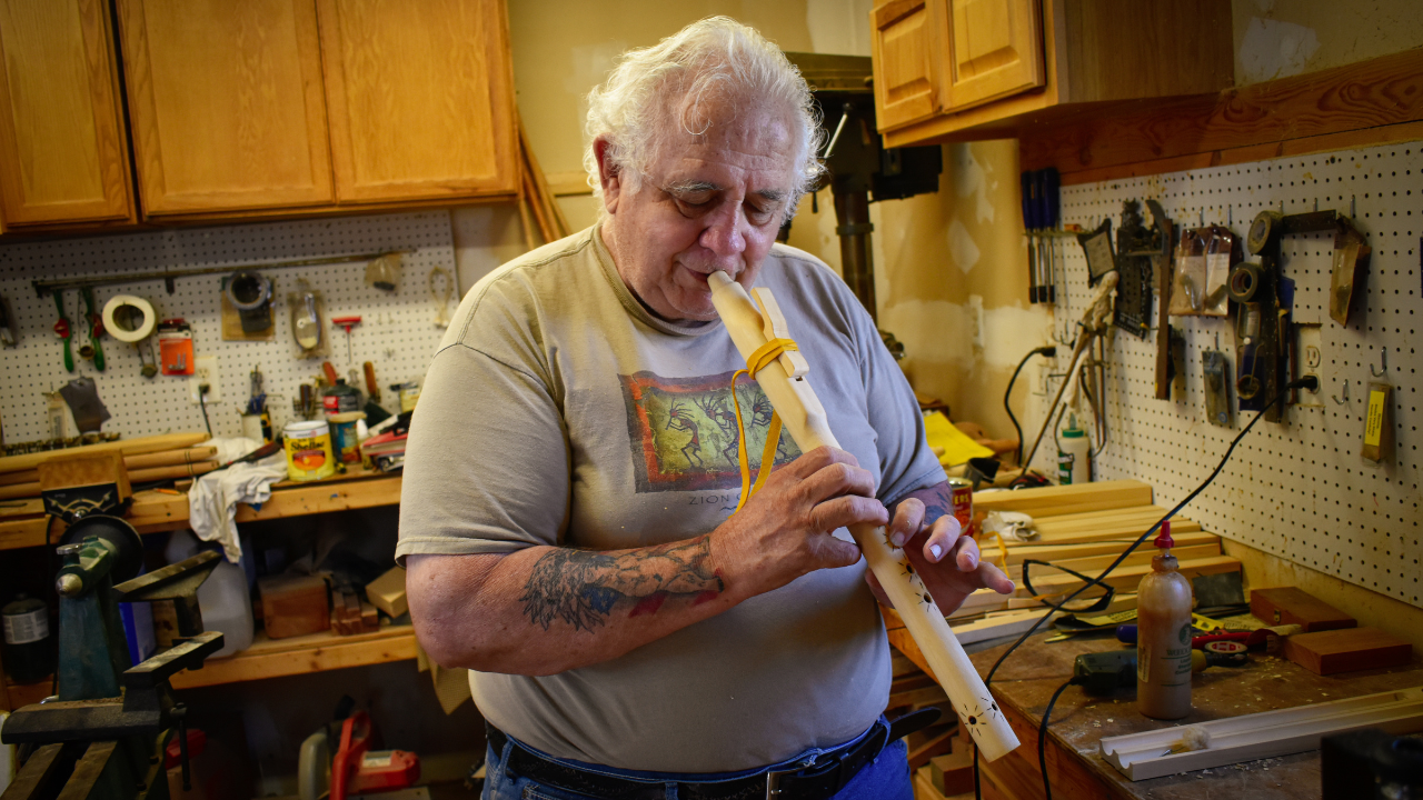 Native American Flute Maker playing the flute in his workshop