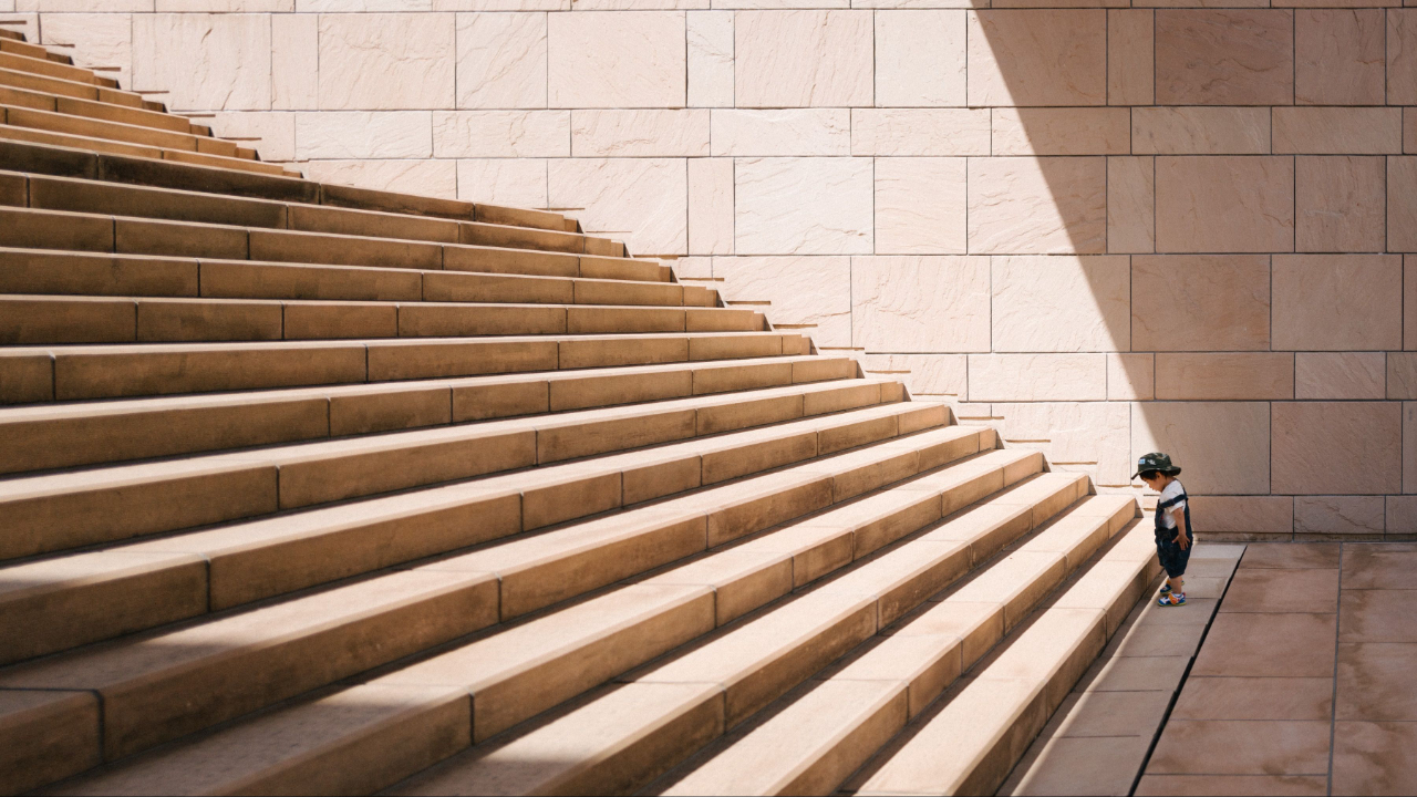 Child stands at bottom of large staircase