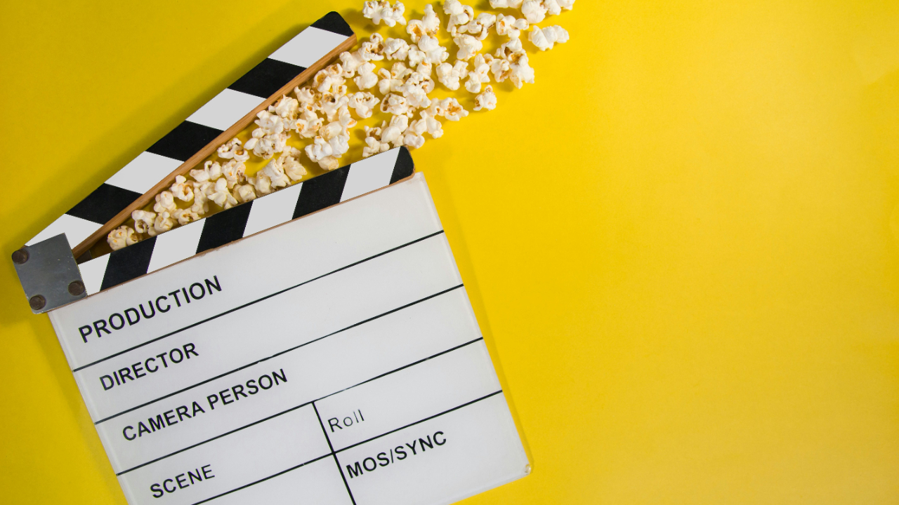 Film clapperboard on yellow background with popcorn