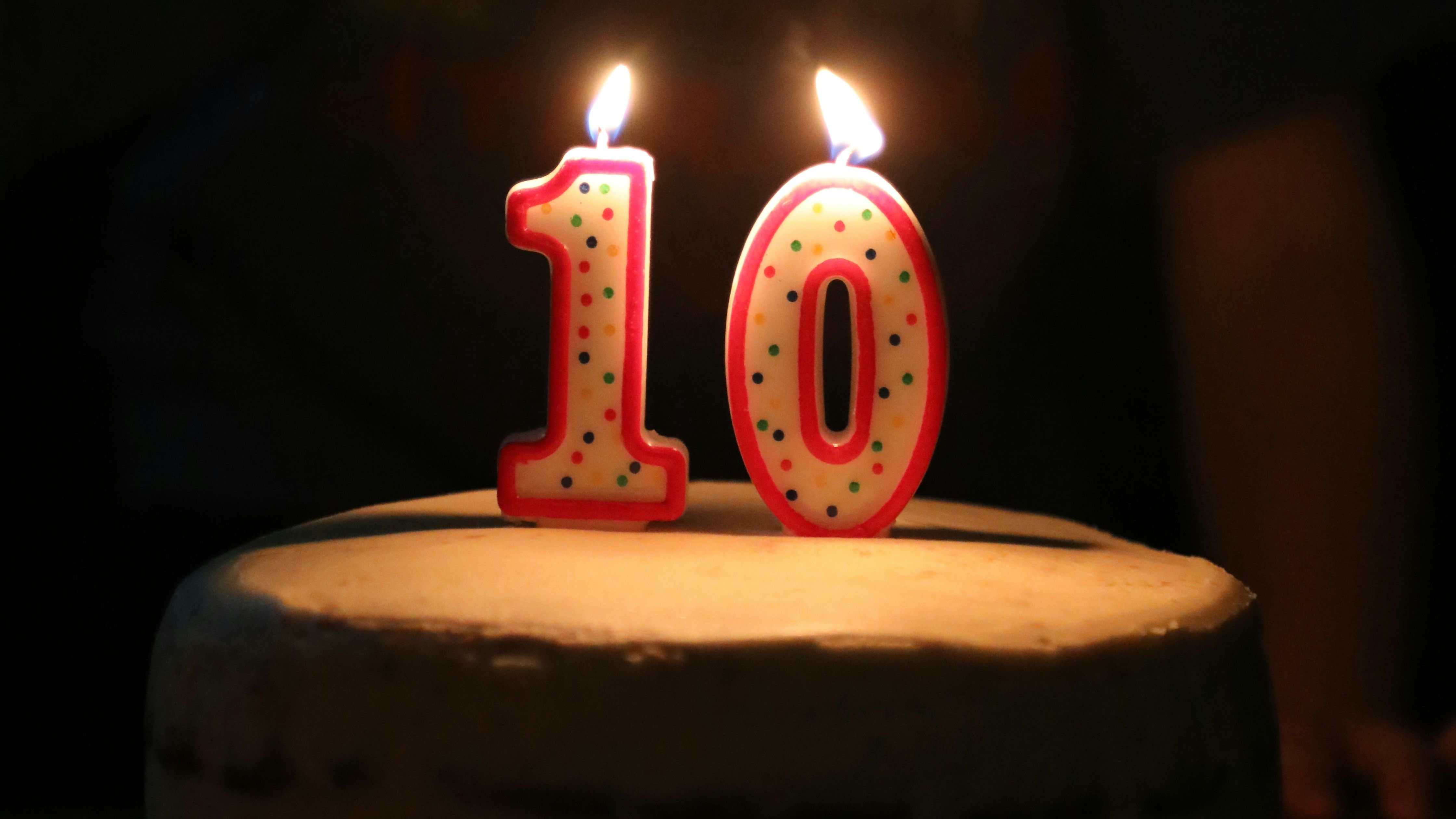 Number ten in lit candles on a cake with dark background