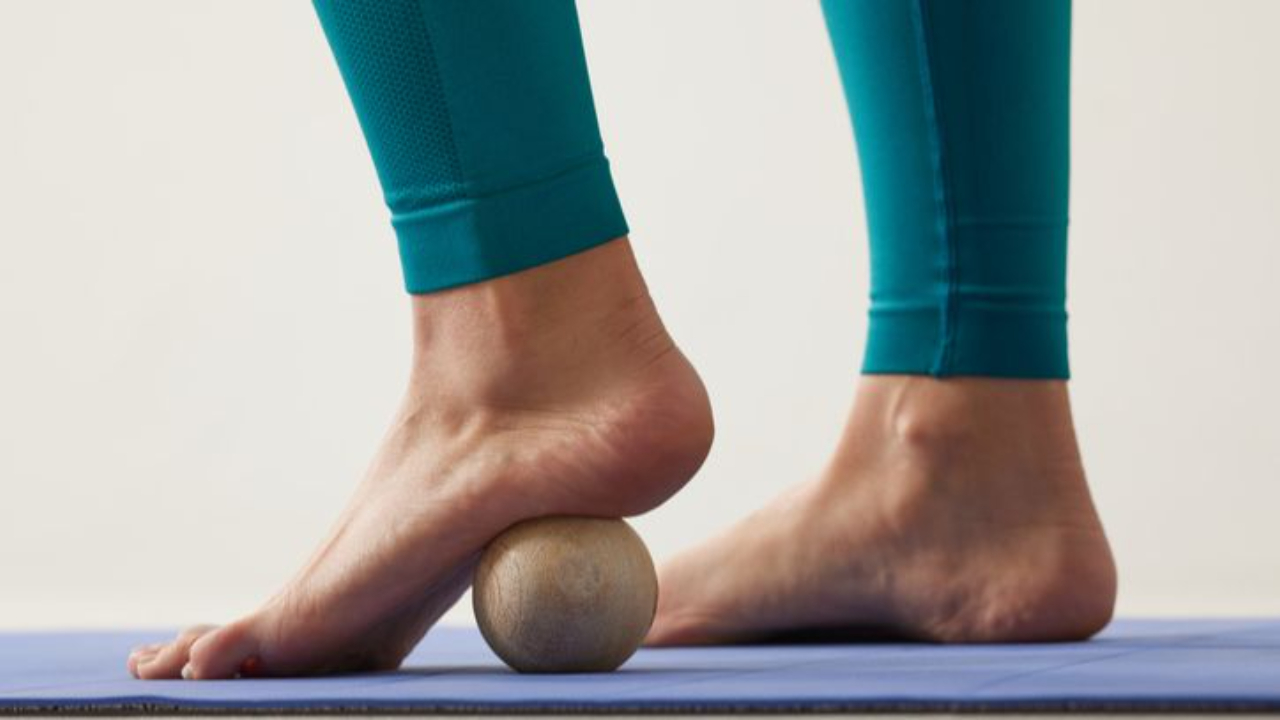This person is rolling their feet on a ball to release the fascia 