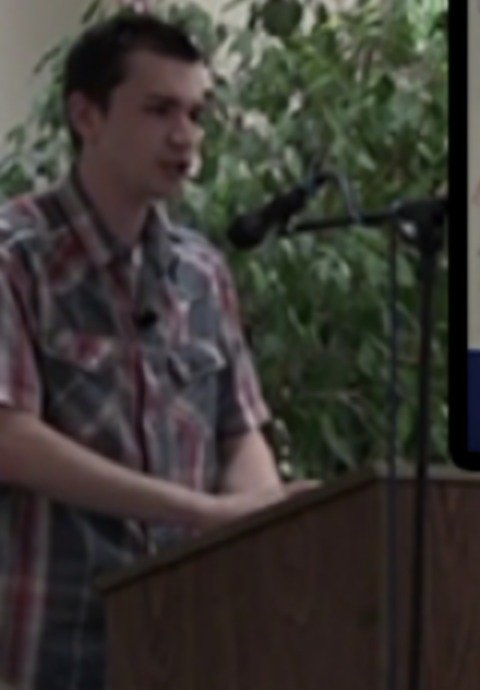Tyler McNamer speaking at a podium during an autism keynote