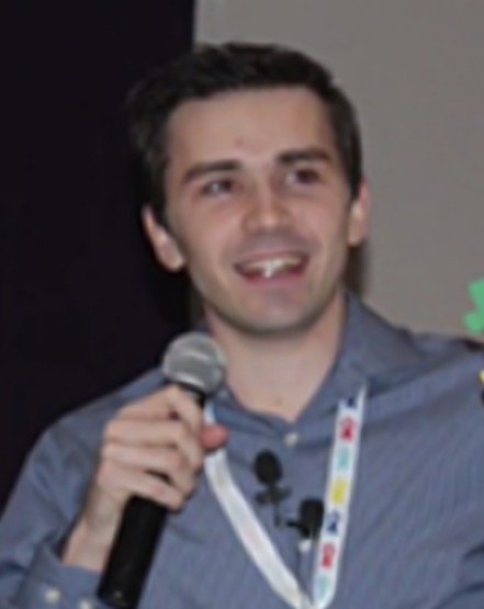 Tyler McNamer smiling while holding a microphone at an event