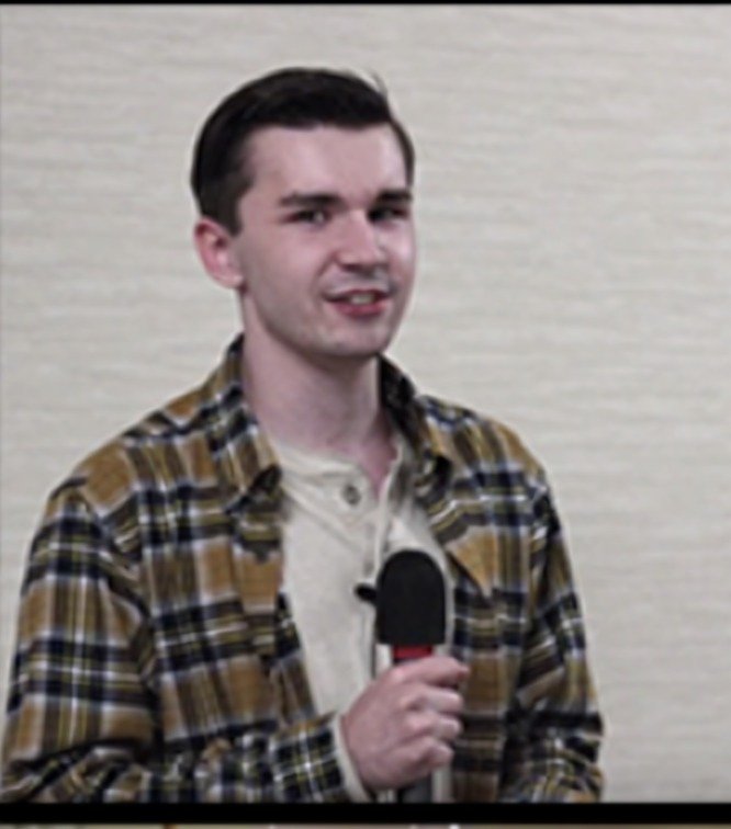 Tyler McNamer with a microphone during his keynote on autism acceptance