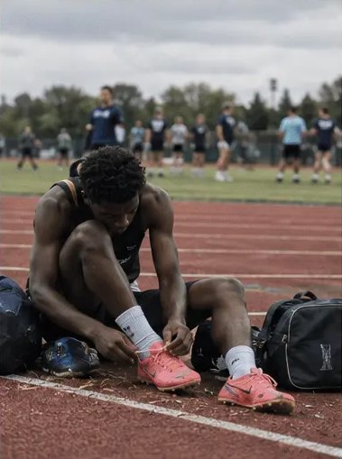 Athlete lacing his spikes trackside