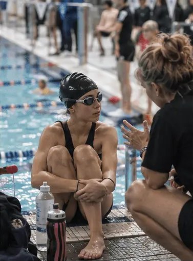 Swimmer talking with her coach poolside