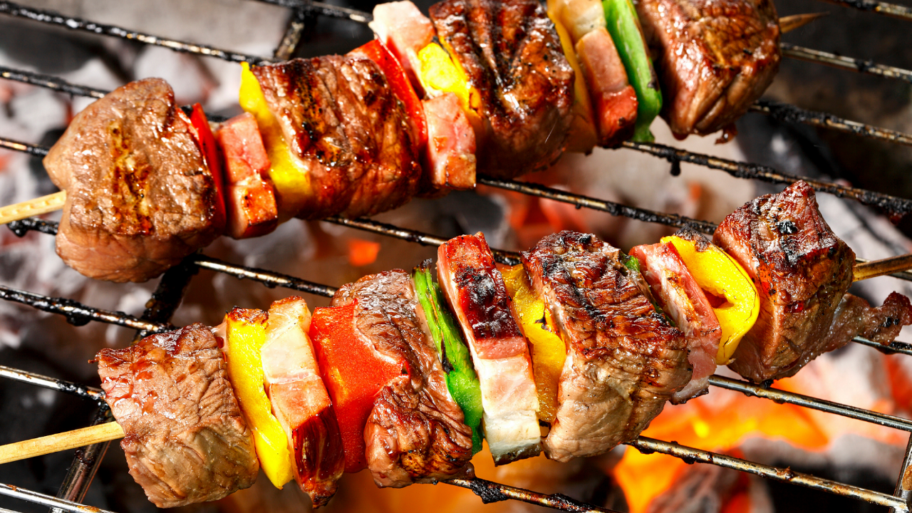 Grilled steak and vegetable kebabs cooking over an outdoor barbecue, representing a casual Jack and Jill couples wedding shower with family-friendly food and relaxed celebration ideas.