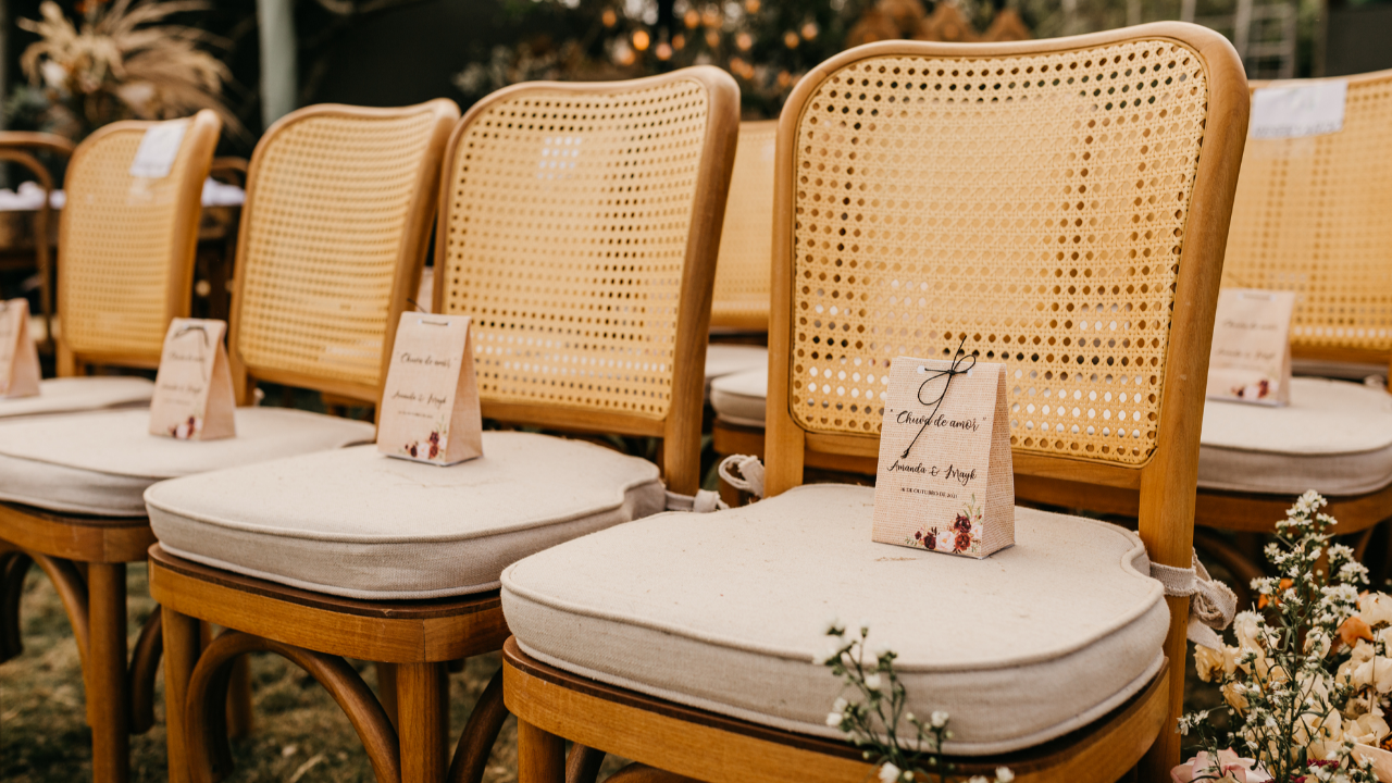Rustic wooden wedding reception chairs arranged in rows with personalized wedding favor boxes placed on each seat, creating a thoughtful and elegant thank-you gift display for guests at an outdoor wedding celebration.