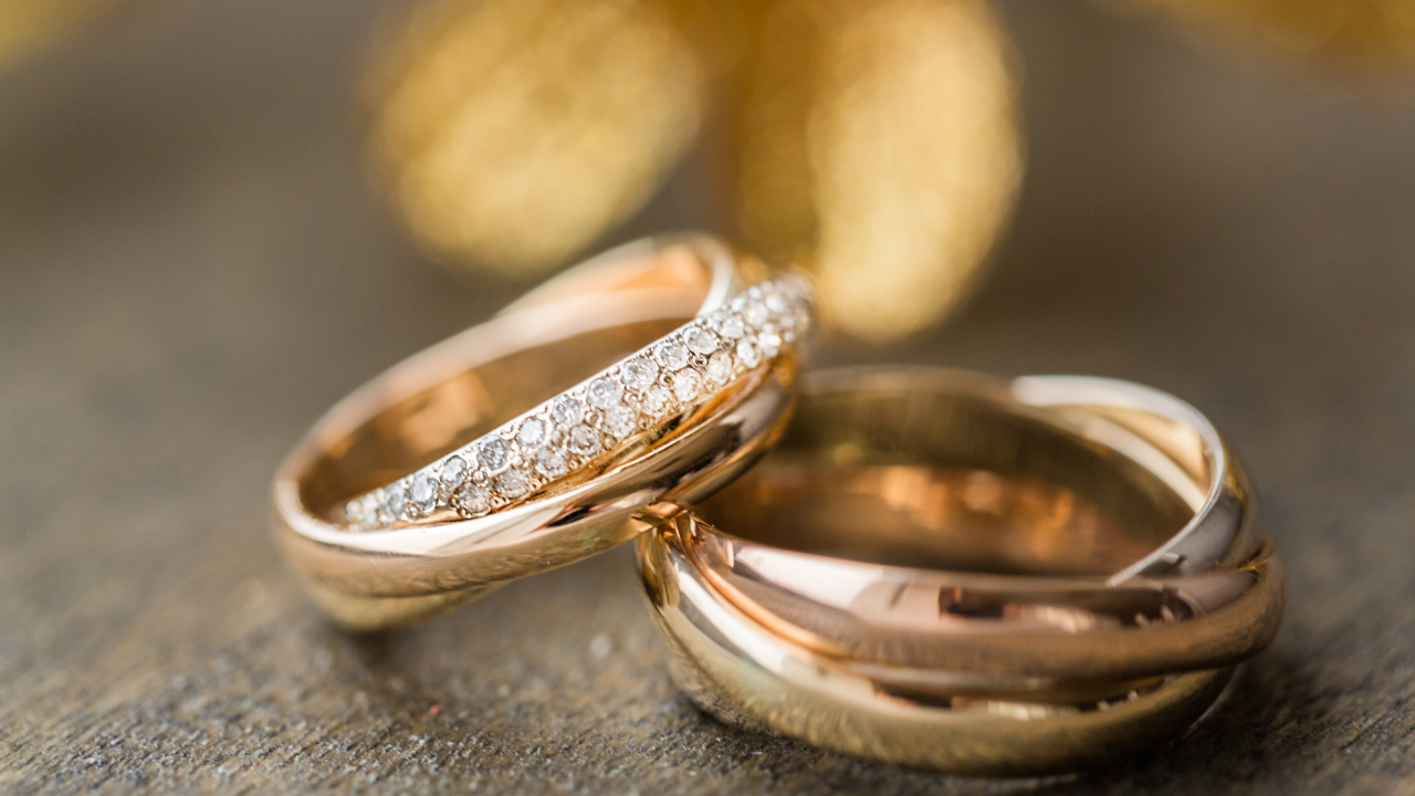Rose gold wedding bands resting together on a wooden surface with soft golden lights in the background, symbolizing eternal love and commitment for an LDS wedding couple.