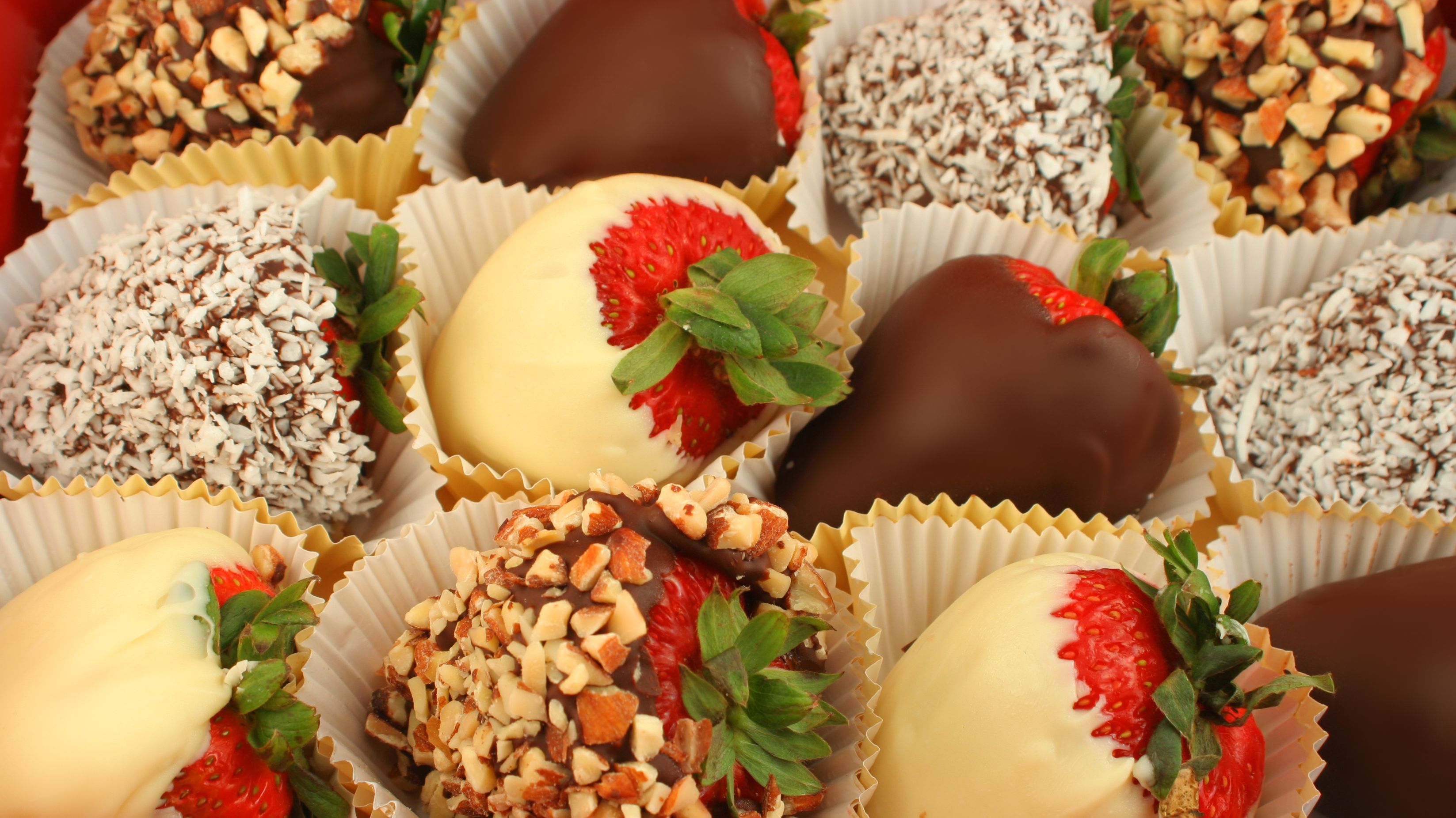 Assorted chocolate-covered strawberries decorated with white chocolate, dark chocolate, coconut, and chopped nuts, displayed as an elegant and budget-friendly wedding favor idea for guests at a wedding reception.