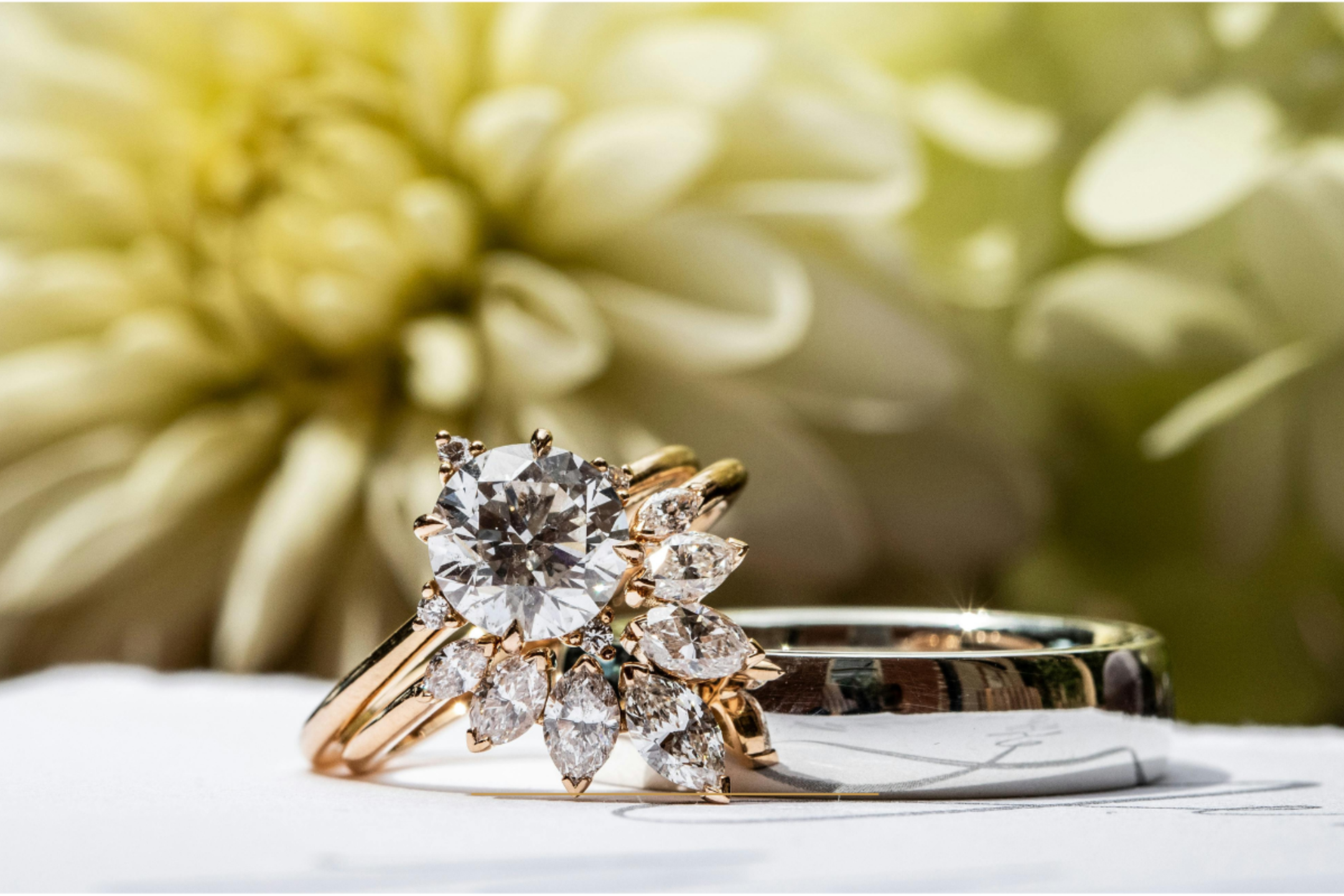 Close-up of elegant gold LDS wedding rings with diamond setting and soft floral background, symbolizing eternal love and covenant marriage in the Church of Jesus Christ.