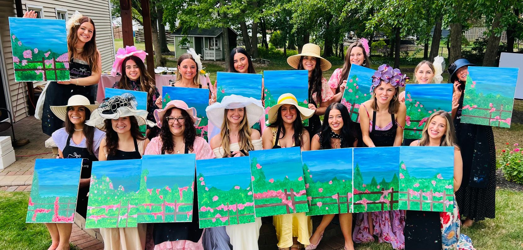 Group holding finished canvas paintings at a Cleveland paint and sip party
