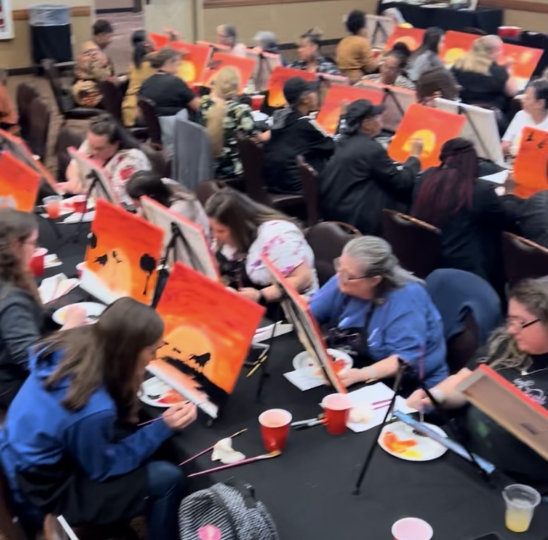 Corporate team in Cleveland holding finished paintings at a team building event