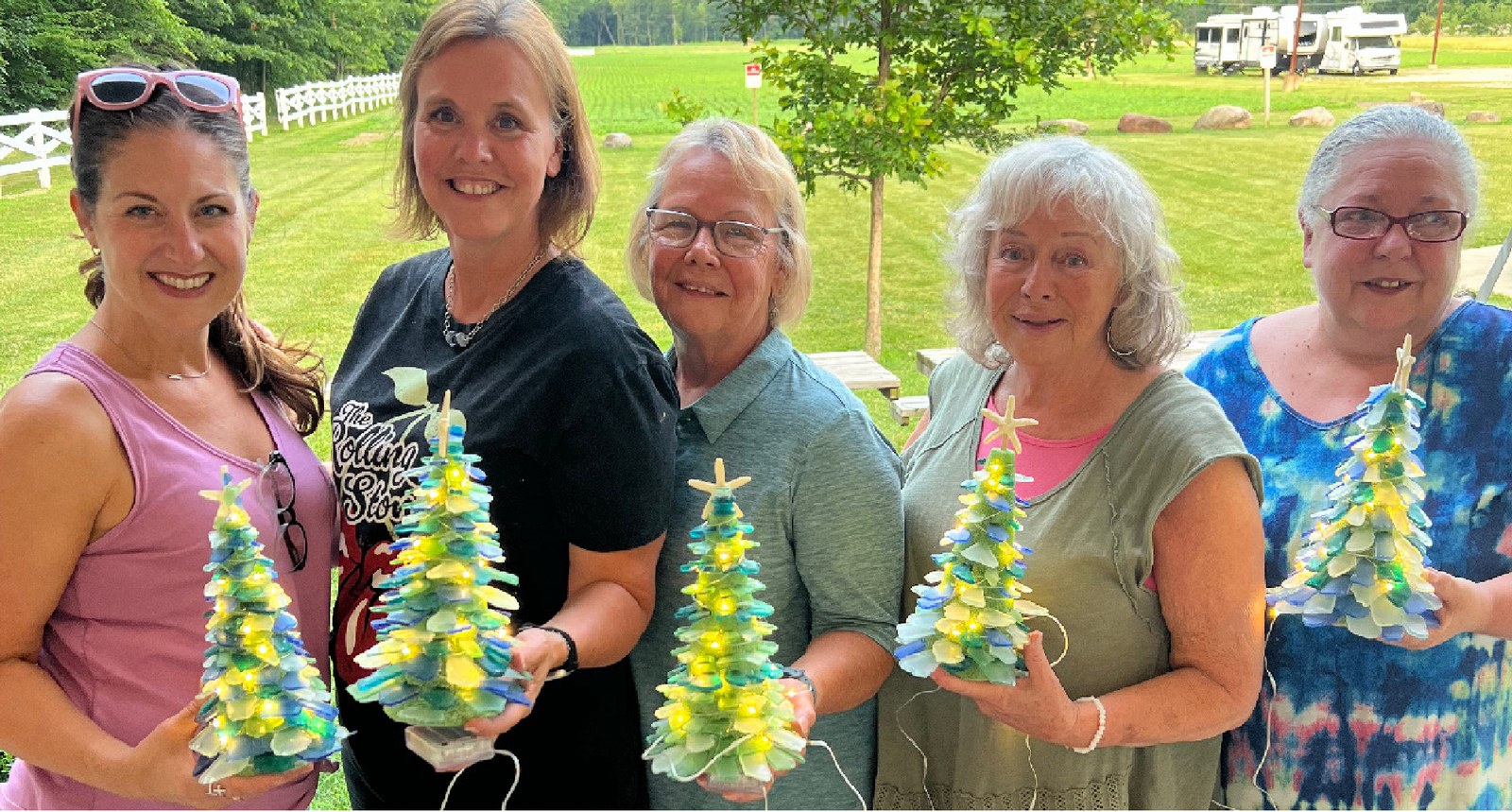 Adults holding lighted sea glass trees they made at a Cleveland sea glass tree party