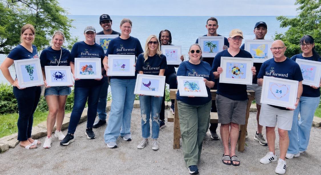 Corporate team in Cleveland holding the framed beach glass collages they created at a team building event