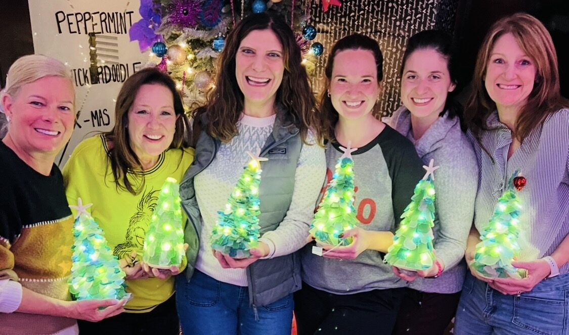 Guests holding their glowing handmade sea glass trees at an Artist at Heart event in Cleveland