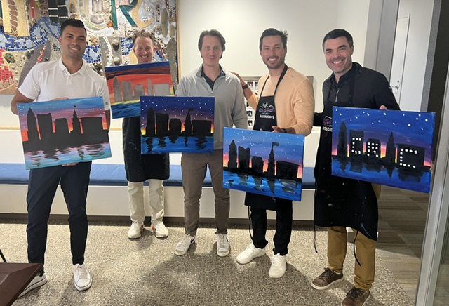 Group at a private paint and sip event in Cleveland holding finished paintings