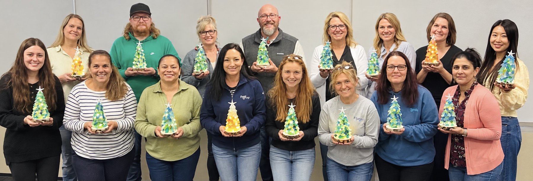 Corporate team in Cleveland holding the sea glass trees they built at a team building event
