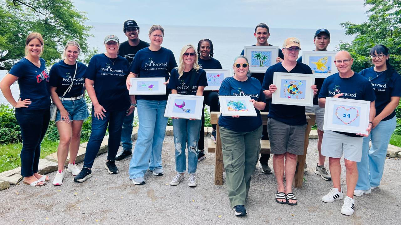 A diverse group of coworkers holding the beach glass art they created at a Cleveland team building paint party