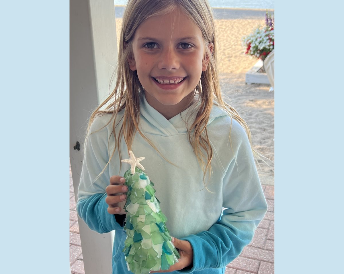 A young guest holding a small green sea glass tree she made, at the beach near Cleveland