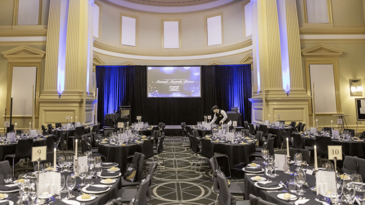 Corporate awards dinner venue set with round tables, a stage and event lighting