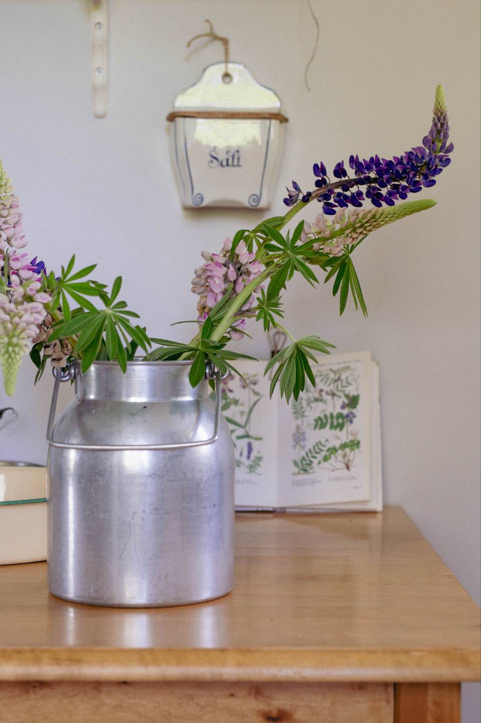 Milchkanne mit Lupinen und Laterne auf einem Tisch in Schweden