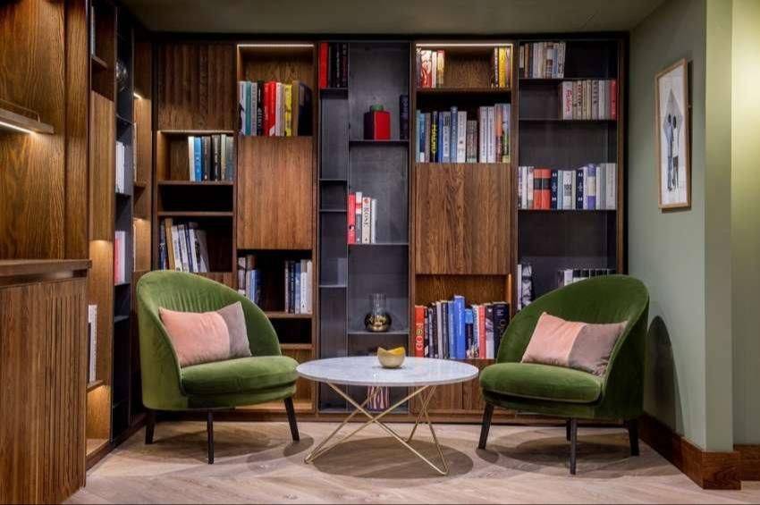 A quiet lounge with green velvet chairs and bookshelves
