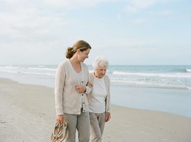 A woman walking arm in arm with her mother along a beach