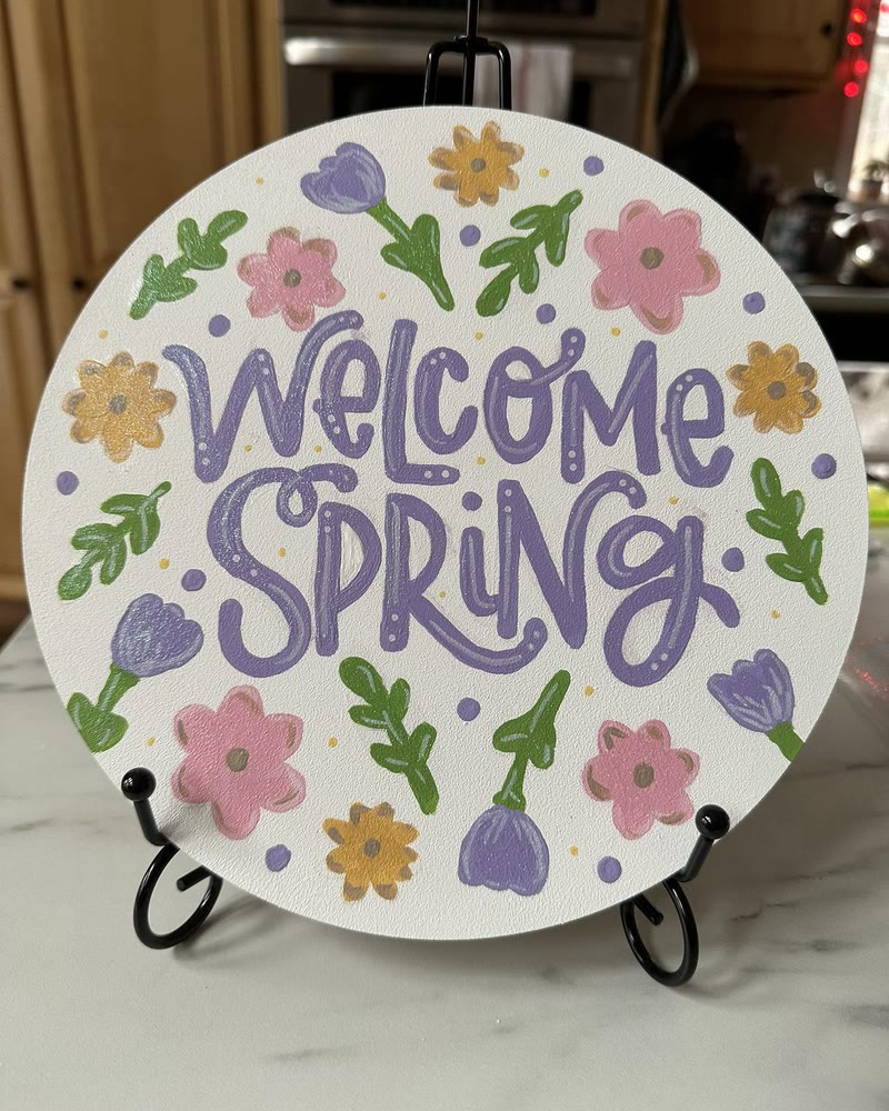 Hand lettered 'Welcome Spring' round sign with flowers, made by a student