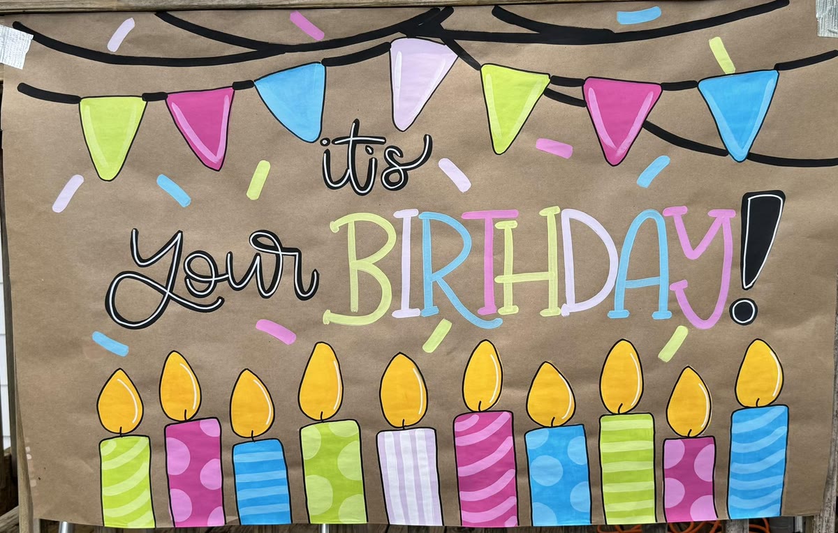 Hand lettered 'It's your Birthday!' paper banner with bunting and candles, made by a student