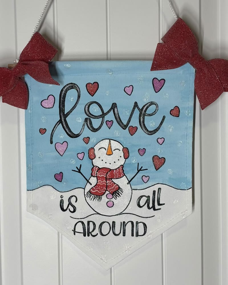 Hand lettered 'Love is all around' snowman banner, made by a student
