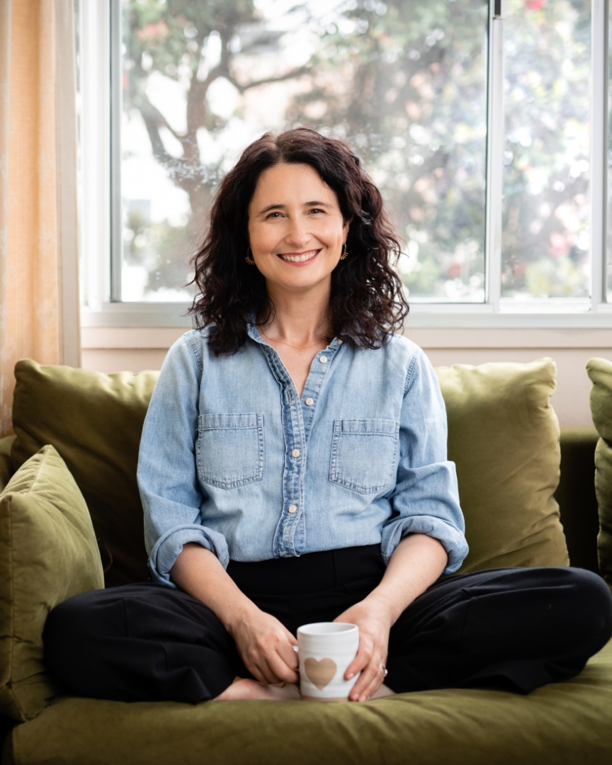 Lea Seigen Shinraku sitting on a sofa with a mug