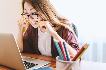 Stock photo of woman at desk bitting pencil