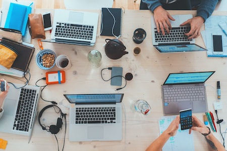 stock photo of desk with laptops and people working